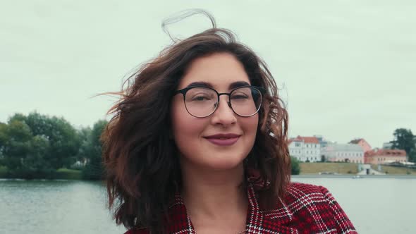 A Closeup of the Caucasian Appearance of a Girl in Glasses Corrects the Hair Developing in the Wind