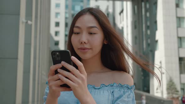 Attractive Asian Woman Looking at Smartphone Excited About Win in Lottery Very Happy and Smiling in