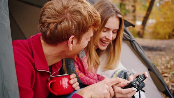 Male and Female Laughing Looking at Camera and Discussing Photos