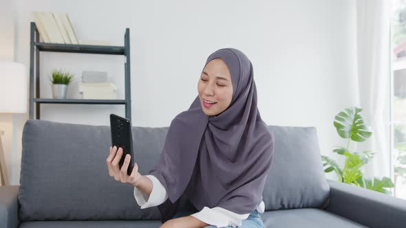 Asian muslim lady wear hijab using phone video call talking with couple at home.