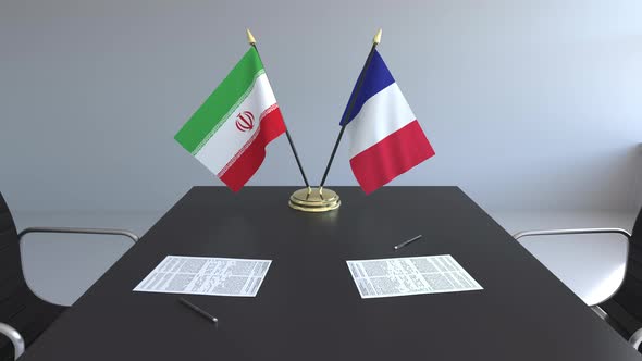 Flags of Iran and France and Papers on the Table