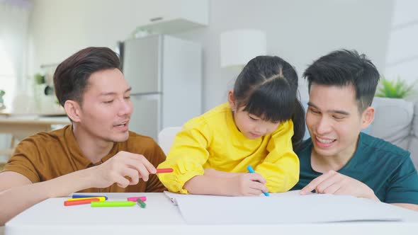 Asian attractive LGBTQ gay family enjoy teach young girl kid draw picture in vacation in house.