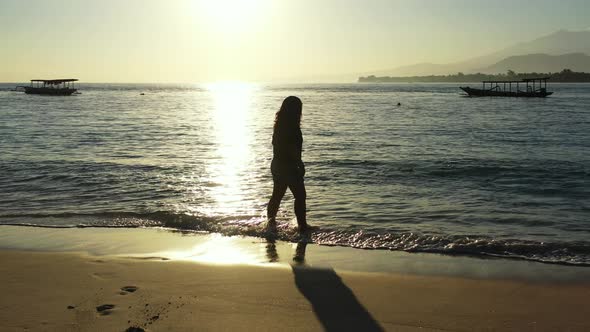 Pretty smiling girl on photoshoot enjoying life on the beach on clean white sand and blue 4K backgro