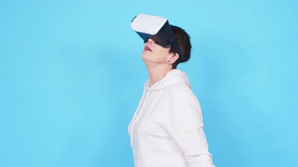 Middle-aged Woman in a White Sweater Watching a Movie with Glasses of Virtual Reality