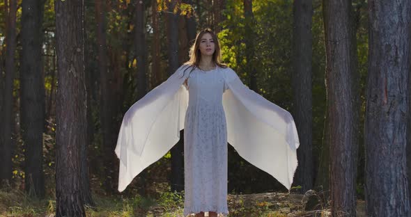 Smiling Brunette Caucasian Woman Raising Up Hands Wrapped in Light White Shawl and Looking Forward