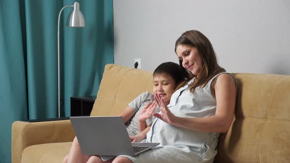 Pregnant Woman and Boy Talking By Video Call on Laptop While Sitting on Couch Slow Motion