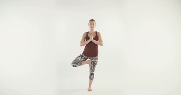 Young attractive woman performing Yoga routine on a white studio background