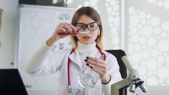 Female Doctor in Medical Uniform Working with Test Tube and Flask Filling with Chemical Solutions