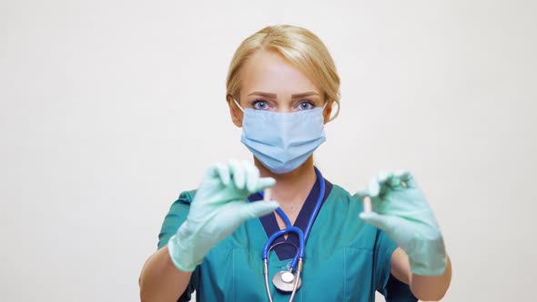 Medical Doctor Nurse Woman Wearing Protective Mask and Rubber or Latex Gloves - Holding Pills