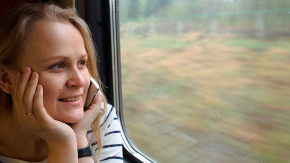 Young Woman Talking On The Phone While Traveling 