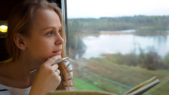 Young Woman Making Notes While Traveling By Train