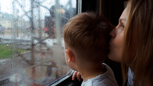 Boy And His Mother Looking Out The Window Of Train alt