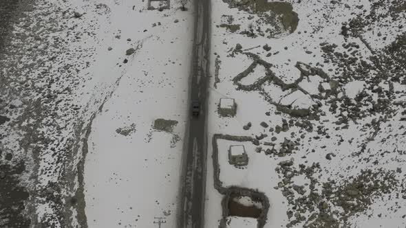 Aerial Birds Eye View Of Black Truck Approaching Bridge On Snow Covered Landscape Of Hunza Valley. P