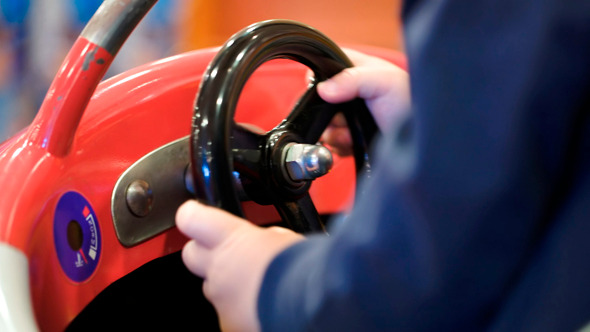 Child Turning Steering Wheel Of A Toy Car