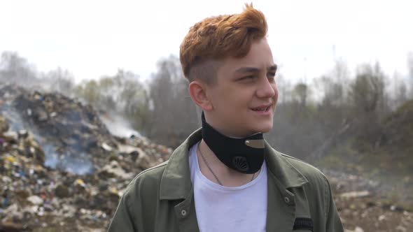 Portrait of young guy looks at camera on huge plastic landfill background