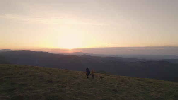 Large Group of Happy Friends on Mountain Top Looking at the Sunset Over Mountain's Valley