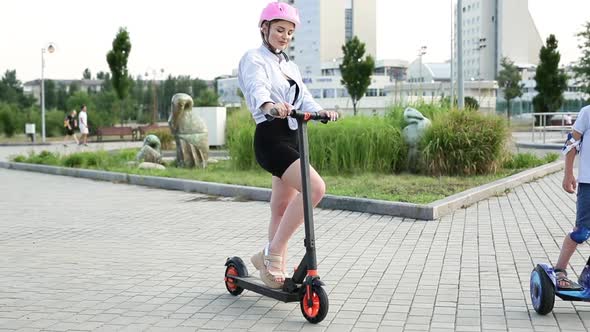 Beautiful Woman on an Electric Scooter in the Park