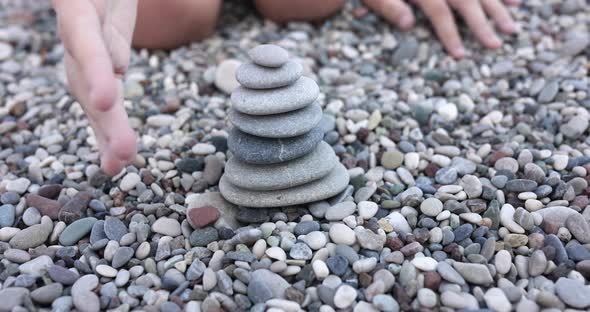 Child Hand Destroying Tower of Stones on Beach Closeup  Movie Slow Motion