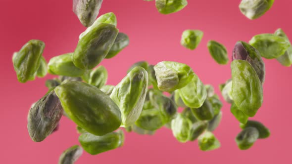 Flying of Peeled Pistachios in Light Fuchsia Background