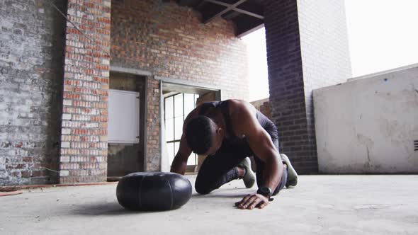 African american man resting after exercising with medicine ball in an empty urban building