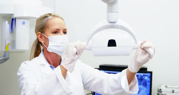 Female dentist adjusting dental lights