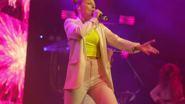 Young Woman Singer in White Clothes Emotionally Sings and Moves on the Stage at Live Concert