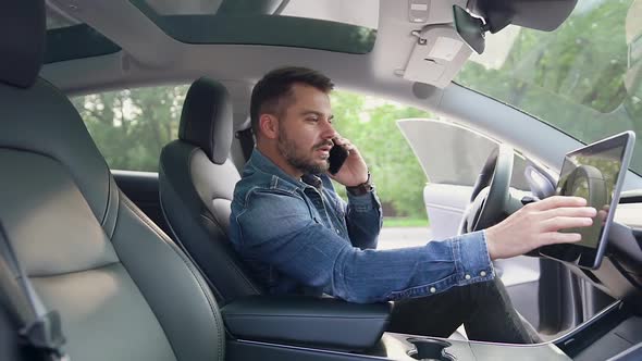 Man Sitting in front of Helm of Own Luxurious Car, Talking on Phone and Using gps Navigator