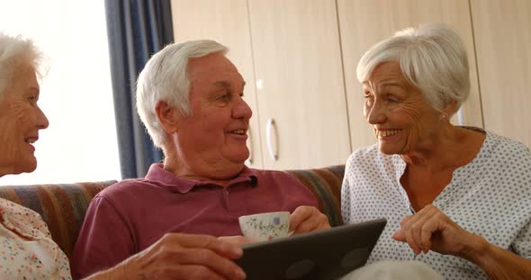 Senior friends discussing together with a digital tablet