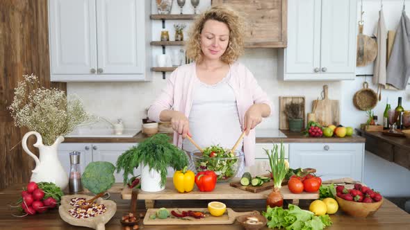 Happy Pregnant Woman Cooking Healthy Salad In Kitchen