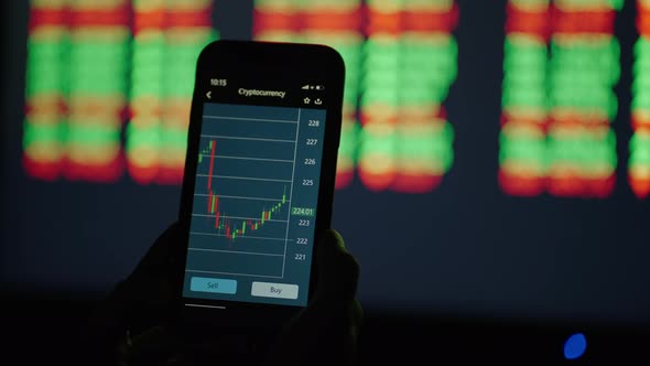 On the Screen of a Mobile Phone the Chart Changes and Shows the Growth and Fall of Stocks Against