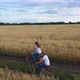 Girl with a Guy Riding a Bike Along a Wheat Field - VideoHive Item for Sale