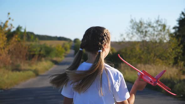 Small Female Child Running with Plane in Hand Through Countryside Road