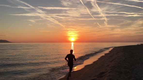 Guy running at the beach during sunset 