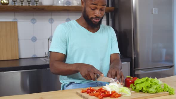 African Young Man Crying Chopping Onion for Vegetable Salad in Kitchen
