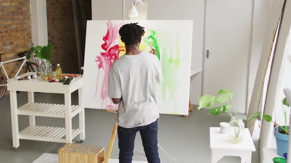 Rear view of african american male artist painting on canvas at art studio