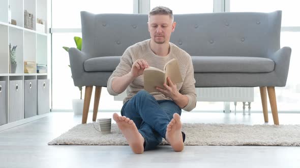 Man Reading Book on a Floor