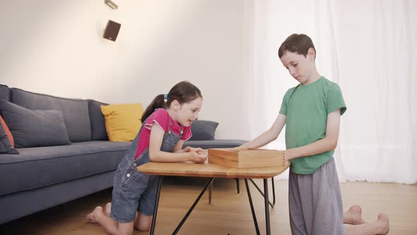 Boy and girl playing a wooden table game at the living room together