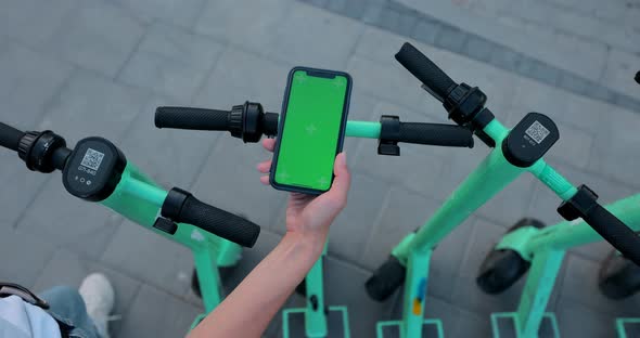 Woman hand click phone with chromakey on background of electric scooter