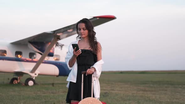 Young Woman with a Phone in Her Hands on the Background of the Plane