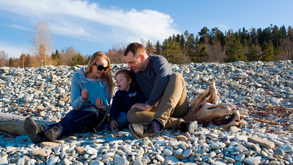 Family Of Three Sitting On The Stony Shore