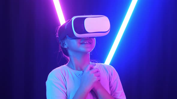 Excited Asian Young Girl Using Virtual Reality Headset And Feel Scary With Neon Light