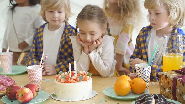 The Birthday Girl Looks Forward To the Birthday Cake Stands Surrounded By Friends