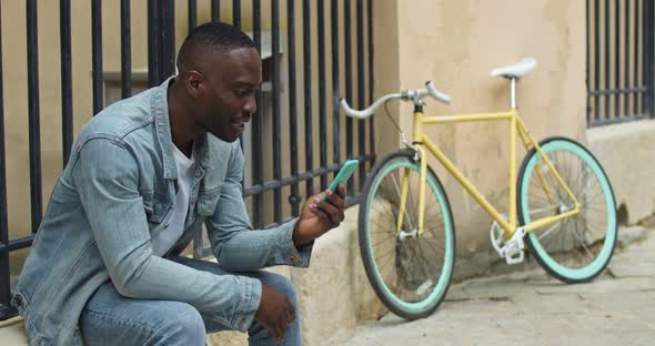 Smiling African American Young Guy Having a Video Call Via His Smartphone, Waving and Smiling While