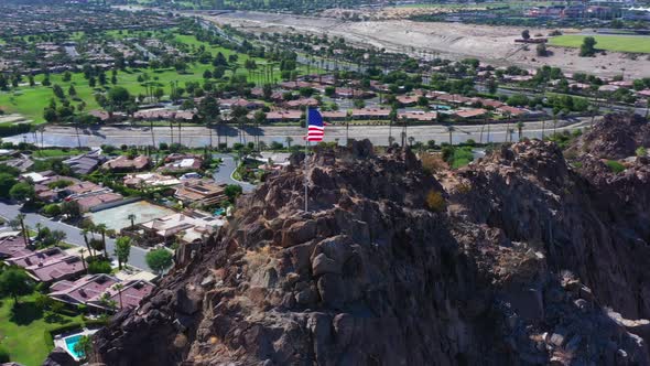 Aerial Shot of American Flag on top of Mountain with City in the Background