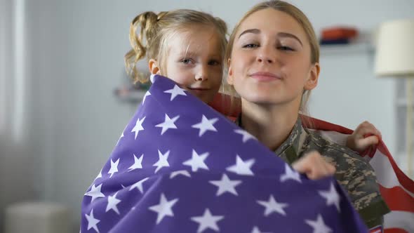 Cute Child With US Flag Embracing Military Mother and Smiling on Camera, Patriot