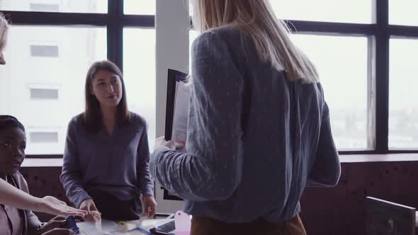 Female Blonde Team Leader Walking Through Office and Controls Work of Employee