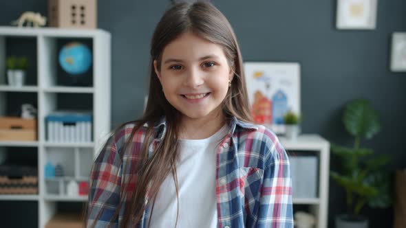 Beautiful Little Girl Laughing and Smiling Looking at Camera with Carefree Face in Apartment