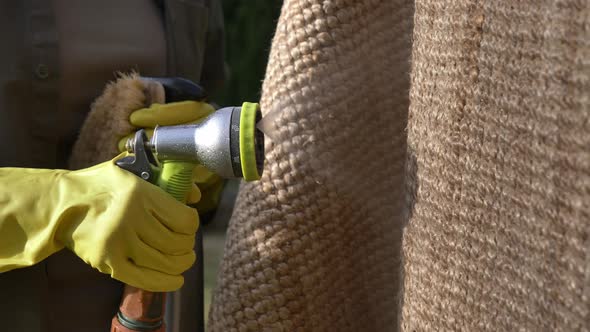 woman wetting an eco-friendly jute rug in by hose water in outdoor