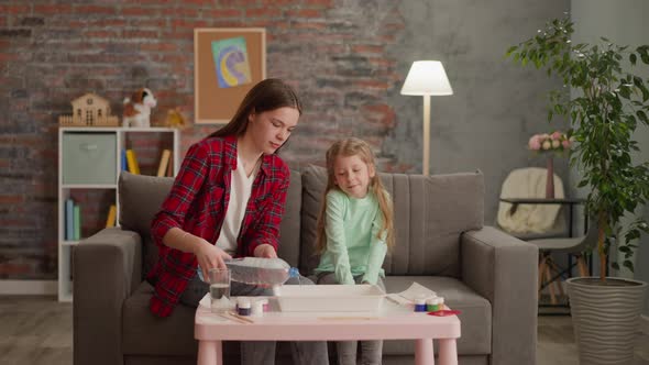 Elder Sister Pours Water for Ebru Drawing with Little Girl