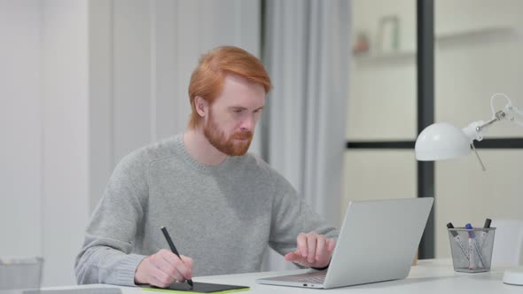 Redhead Graphic Designer Using Laptop and Tablet 